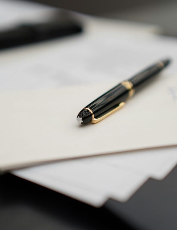 a fountain pen resting on a stack of documents