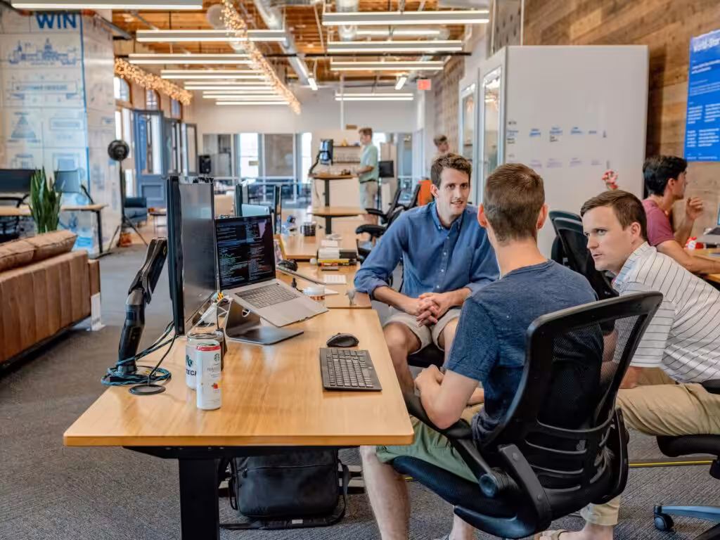 men grouped around a desk having a conversation