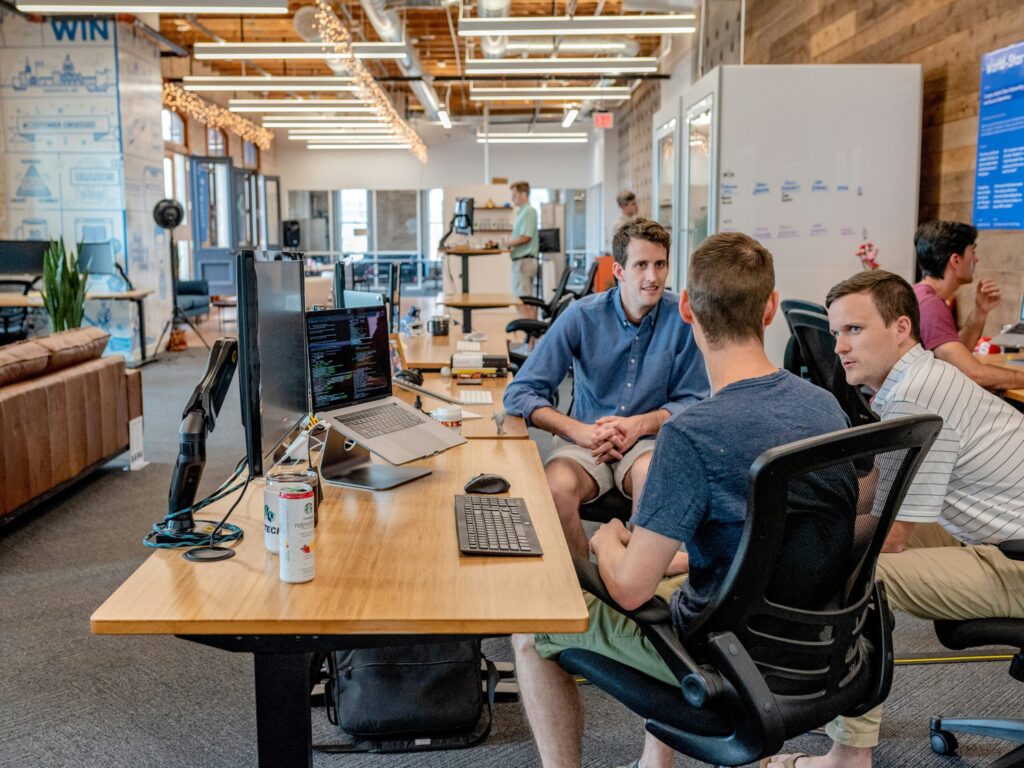 men grouped around a desk having a conversation