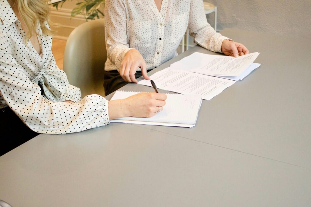 women sitting at a desk signing a document