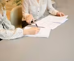 women sitting at a desk signing a document