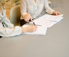 women sitting at a desk signing a document