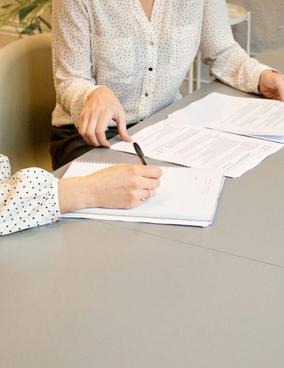 women sitting at a desk signing a document