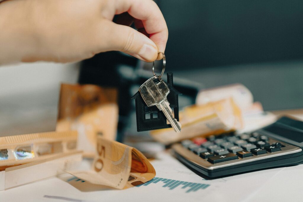 close up of someone handing keys over a table with money and a calculator on it