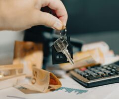 close up of someone handing keys over a table with money and a calculator on it