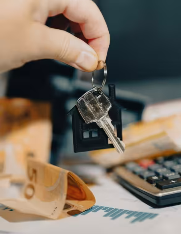 close up of someone handing keys over a table with money and a calculator on it
