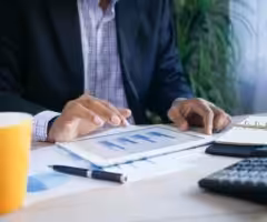 person working at a desk with calculator and financial charts