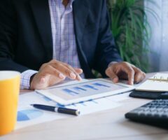 person working at a desk with calculator and financial charts