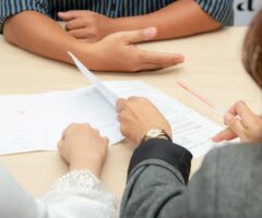 close up on peoples hands and documents on a table