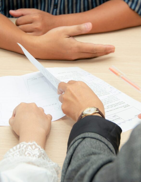 close up on peoples hands and documents on a table